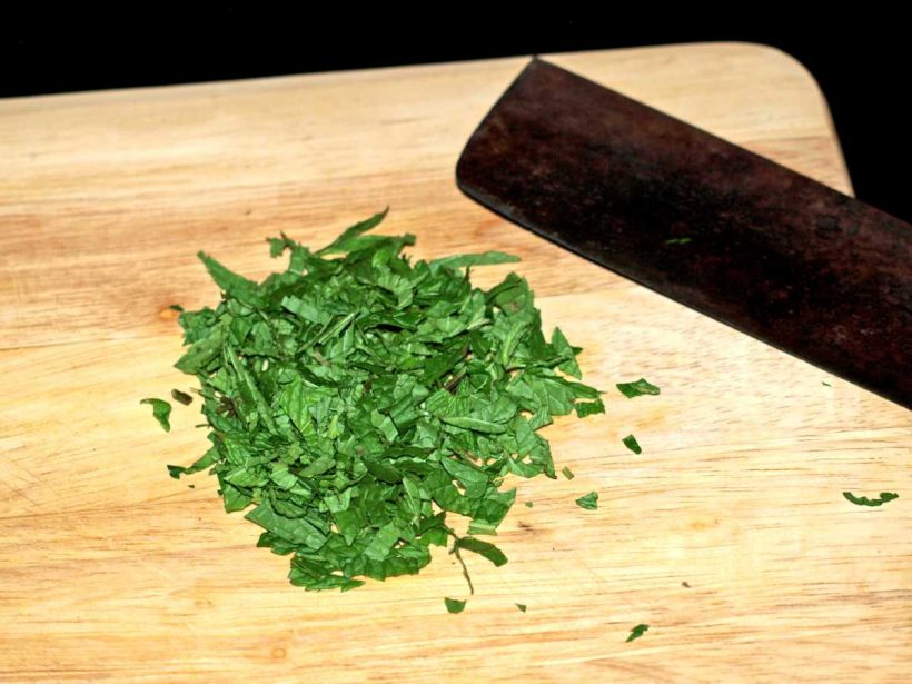 Für Zucchini Salat gebraten die Minze mit einem Messer grob hacken.